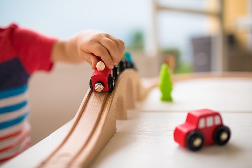 A little boy is playing with wooden trains on a table.
