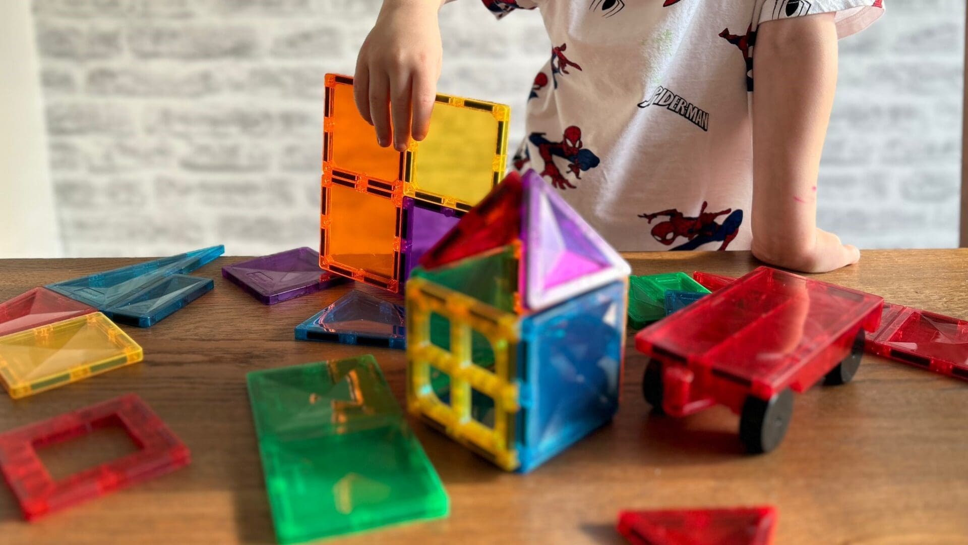A child is playing with a set of colorful magnetic blocks.