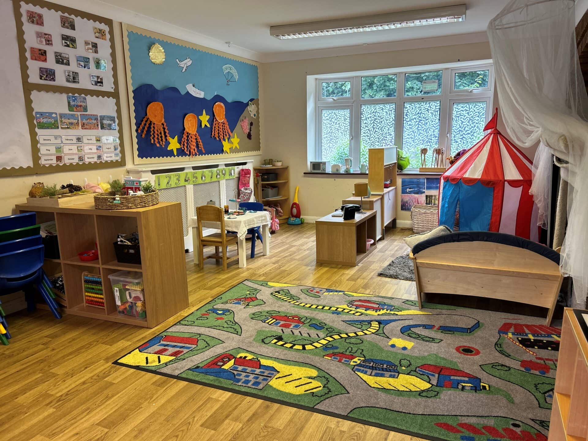 A child's playroom with toys and a rug.